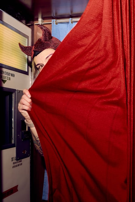 a person wearing a cap with devil horns peeks out of a photo booth