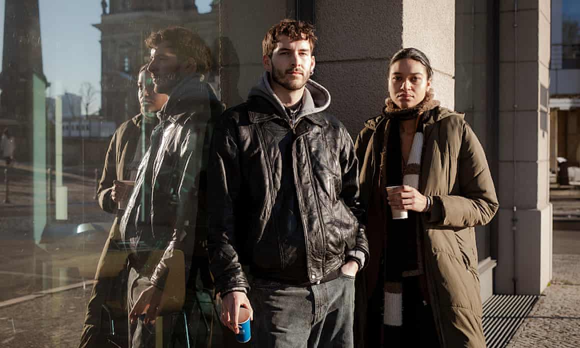 A man and a woman stand beside a reflective building.