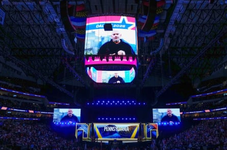 A man speaks on a screen in an arena