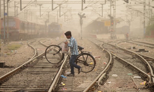 An Indian commuter crosses railway tracks as dust covers sky in Jalandhar.