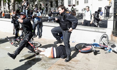 Police officers protect an injured man in Trafalgar Square