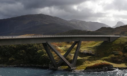 A bridge over a wide expanse of water with a mountain in the background