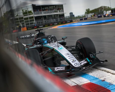 A Mercedes Formula 1 car drives on a race circuit with blue and red striped curbing