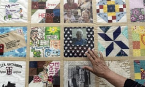 A person reaches out to touch a panel of the COVID Memorial Quilt