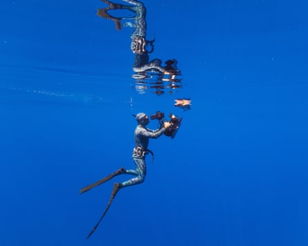 A diver films a loggerhead turtle resting at the surface of the water