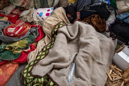 People sleeping under blankets in a tent.