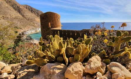 A castle ruin and cacti in the foreground with the San Pedro beach behind
