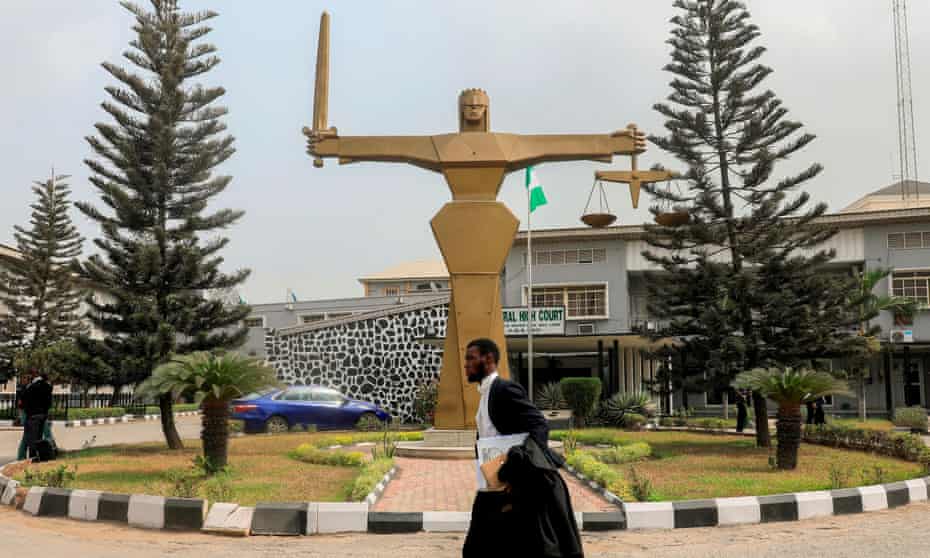 A barrister walks past the statue of Lady Justice in front of the Federal High Court in Lagos, Nigeria.
