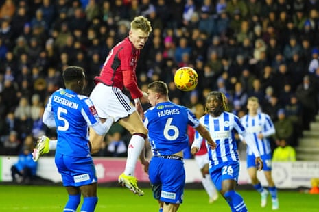 Scott McTominay van Manchester United (tweede van links) kopt de bal langs Charlie Hughes van Wigan Athletic.