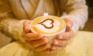 Woman holding hot cup of coffee, with heart shape