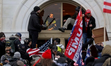 A mob of Trump supporters climb through a window they broke as they storm the US Capitol in Washington on 6 January 2021.