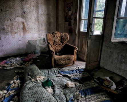 Decrepit grand room with rugs and an armchair