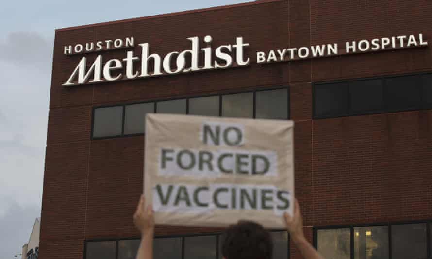 A person holds a sign to protest at Houston Methodist hospital in Baytown, Texas, against a policy that says hospital employees must get vaccinated against Covid-19 or lose their jobs.