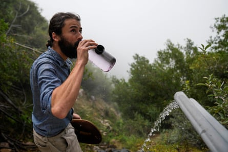 Activist Bridger Zadina drinks spring water flowing from a BlueTriton pipe in the San Bernardino national forest.