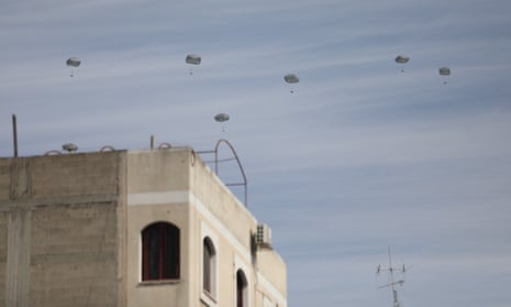 Aid packages with parachutes float down above the Gaza City skyline