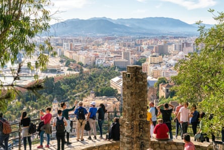 People enjoy views over Malaga city from a viewpoint towards Gibralfaro castle.