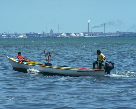 Man and boy fishing in a small boat amid the oil pollution in Lake Maracaibo, Venezuela.