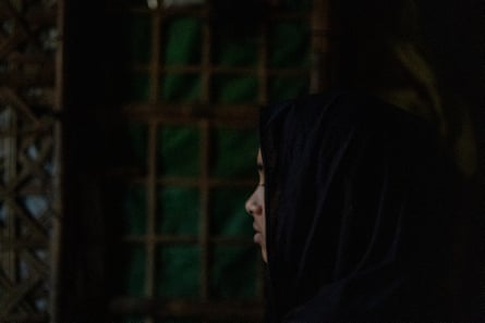 A young woman in a black chador stands in profile.