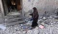 A woman walks through rubble of a building