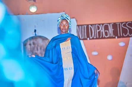 A woman in a headdress models a royal blue robe on a catwalk