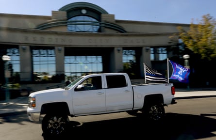 white car with two flags drives past building