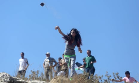 A Palestinian woman throws stones at Israeli soldiers following a protest against expropriation of Palestinian land by Israel in Nabi Saleh village, near Ramallah. 