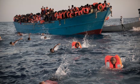 People leap into the water as they are helped by an NGO rescue operation in the Mediterranean near Libya