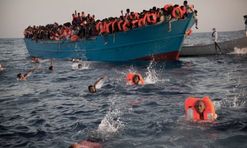 Migrants, many from Eritrea, jump into the water from a crowded wooden boat as they are helped by members of an NGO during a rescue operation in the Mediterranean sea about 13 miles north of Sabratha in Libya, August 2016. 