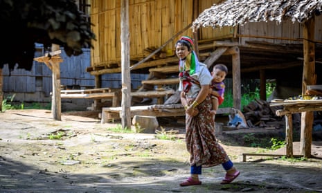 A long neck Karen woman carries a baby on her back in Baan Tong Luang hill tribes village