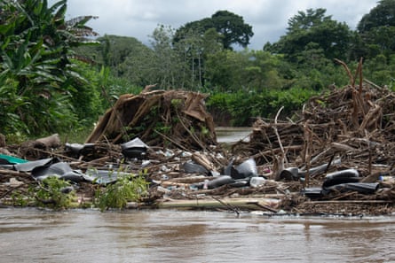 Piles of plastic and other waste piled up against a bank of a river