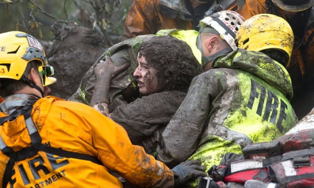 Firefighters carrying a woman rescued from a collapsed house after a mudslide in Montecito