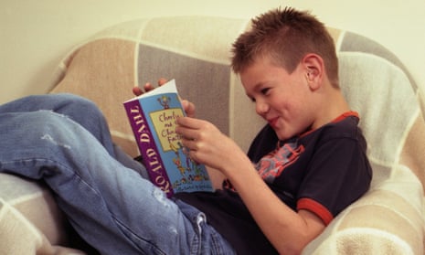 A boy reading Charlie and the Chocolate Factory by Roald Dahl