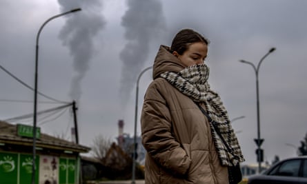 A girl wears a scarf over her face as she walks past a factory in Skopje.