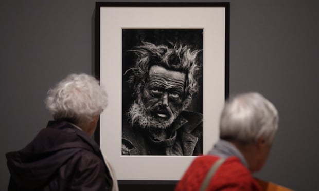 Visitors look at a 1970 photograph of a homeless Irishman in east London by Don McCullin.