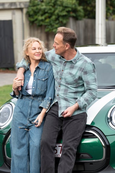Charlene (Kylie Minogue) and Scott (Jason Donovan) sitting on a green Mini in the Neighbours finale