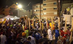 Volunteers bring pieces of wood to help prop up sections of the collapsed building.