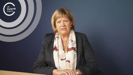 Heather Hallett gives a statement to the inquiry. She is in her 70s with blond hair cut into a bob and fringe. She wears a dark grey jacket and a cream scarf with a pattern of dogs on it, and sits against a dark grey wall with the inquiry’s logo on it.