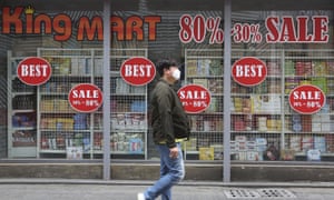 A man wearing a face mask walks by sale signs at a shopping district in Seoul, South Korea.
