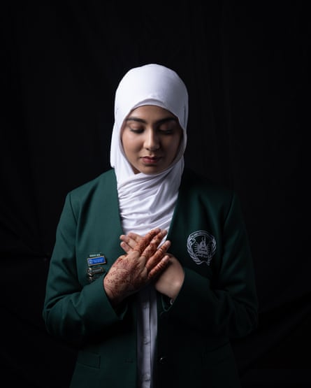 A student from the Islamic College of Brisbane in uniform, holding her hands over her heart and looking down