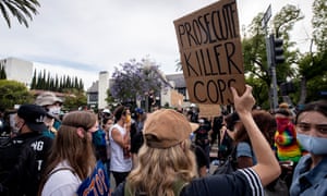 A protester holds a placard reading ‘Prosecute Killer Cops’ in front of Los Angeles mayor Eric Garcetti’s house.