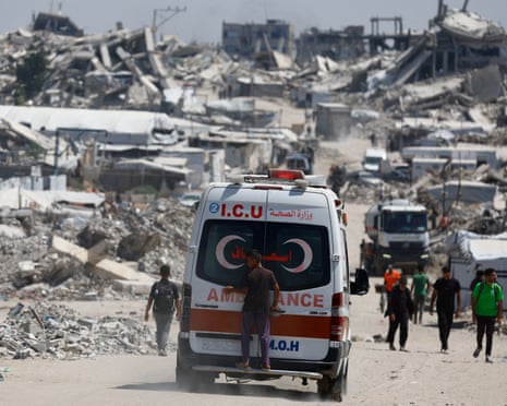 A person rides on the rear of an ambulance in Gaza