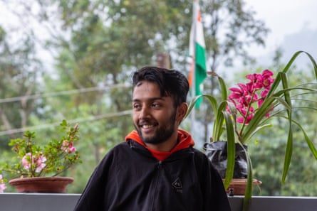 Portrait of Bikram Bhattarai smiling in front of a wall with potted flowers on it