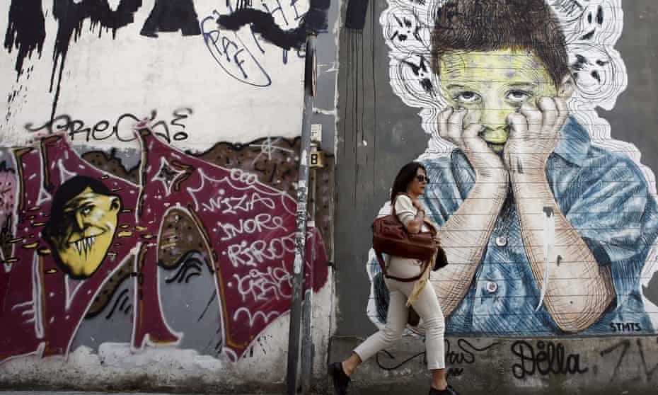 A pedestrian walks past a graffiti in central Athens, April 26, 2015. REUTERS/Kostas Tsironis