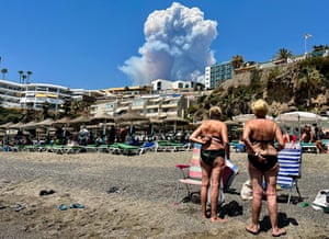 People on Playa el Bajondillo, in Torremolinos, looking at smoke from a wildfire in Malaga on 15 July 2022.