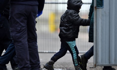 A UK immigration enforcement officer escorts a child migrant in Dover.