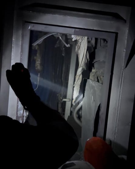 A man’s arm silhouetted against a damaged door