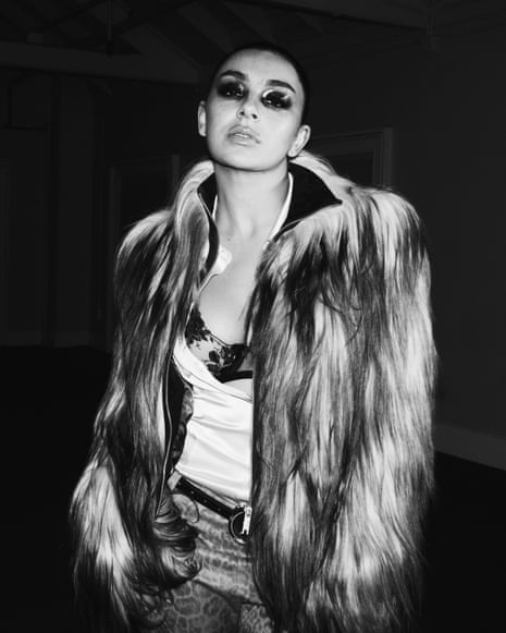A black and white portrait of Charli xcx wearing heavy eye makeup and a fur coat