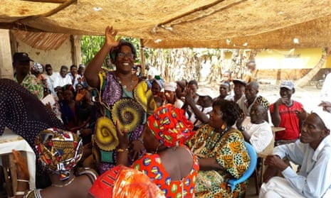 Sierra Leonean politician Femi Claudius Cole speaks to women and men in traditional west African dress under a canopy