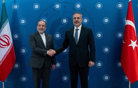Araghchi and Fidan shake hands while standing alongside their country's flags