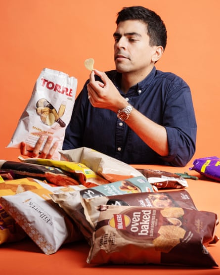 A man holds a crisp up from a packet.